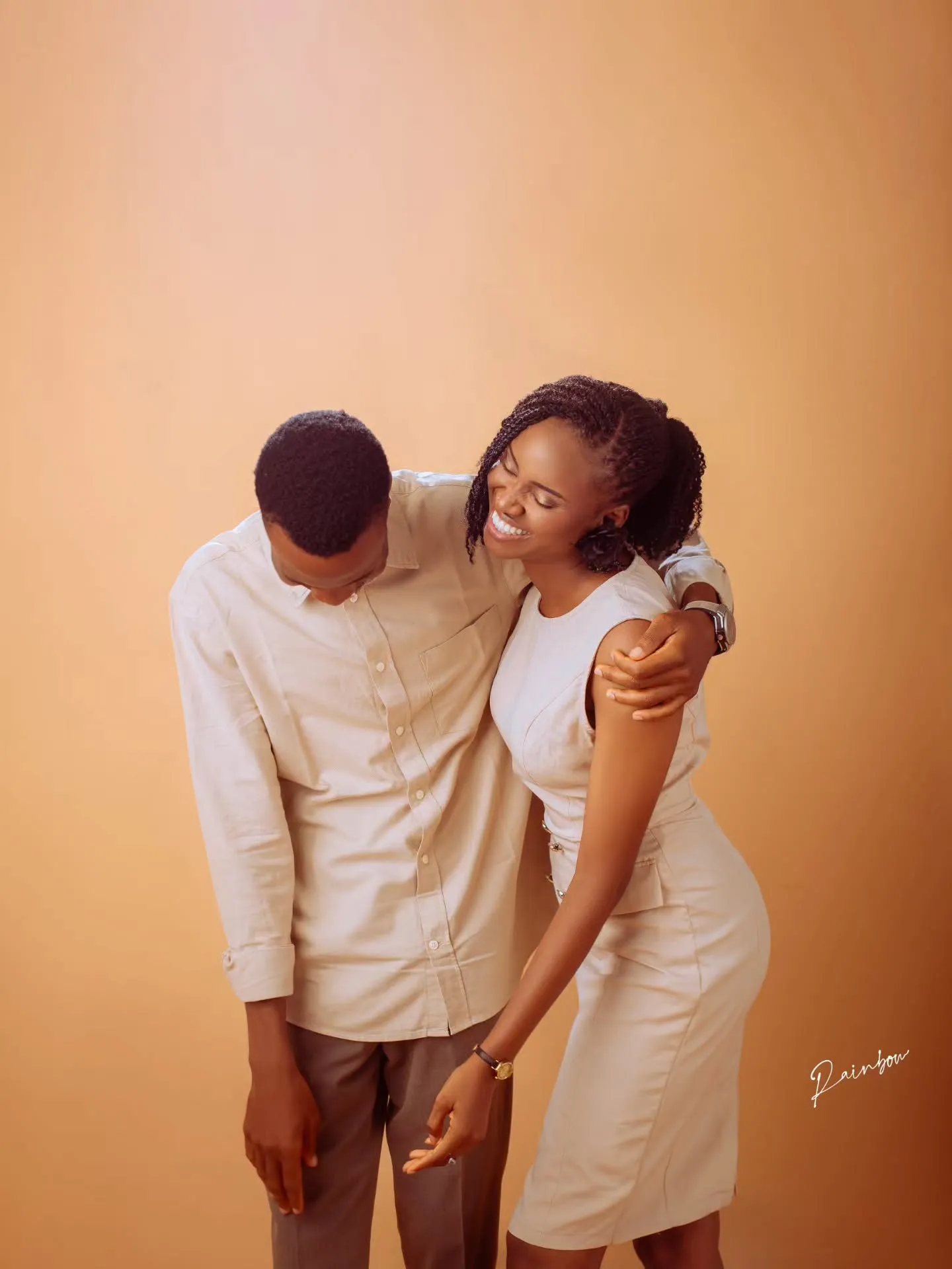 Couple laughing together in cream outfits