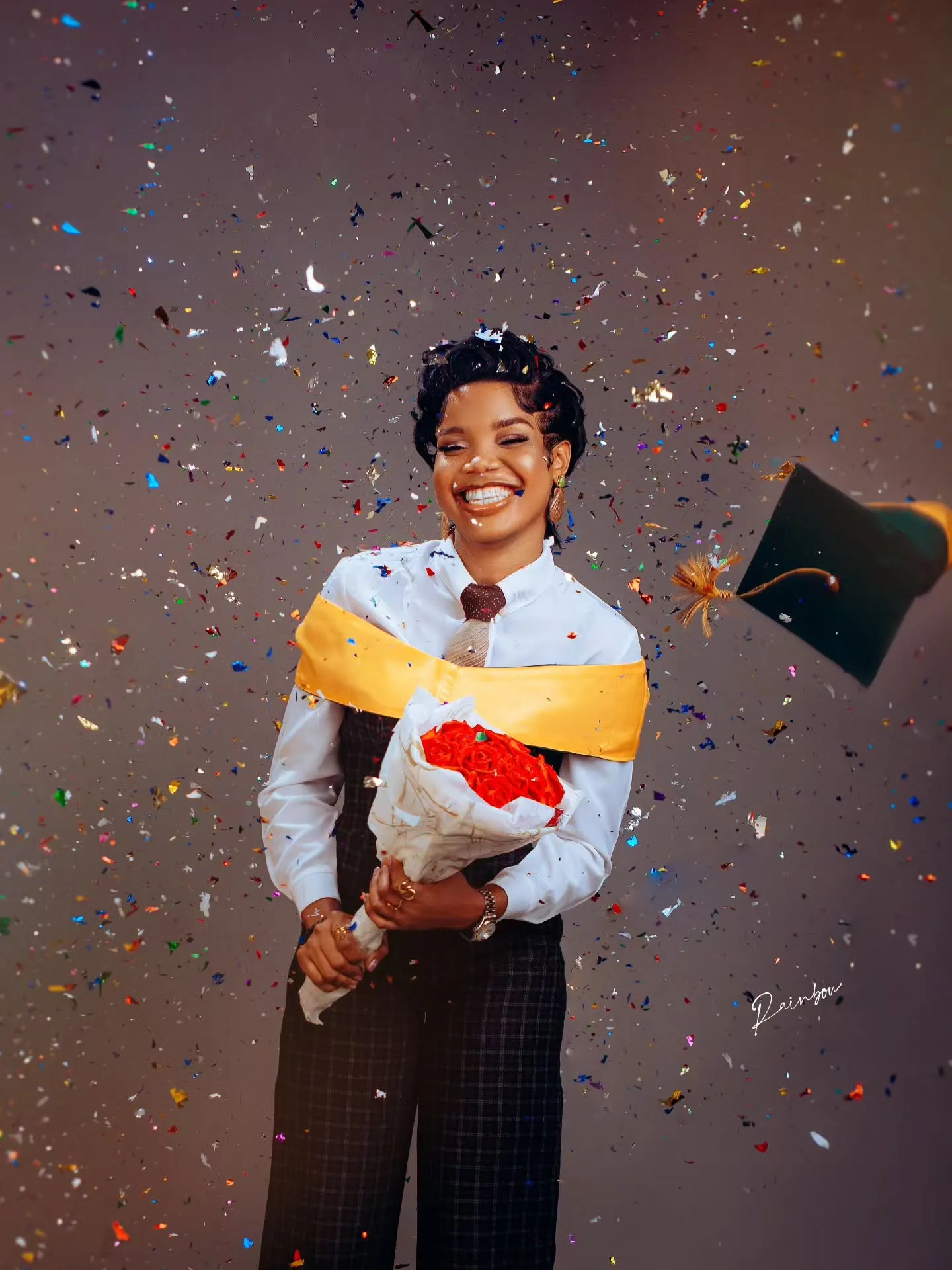 Graduate holding flowers as confetti falls