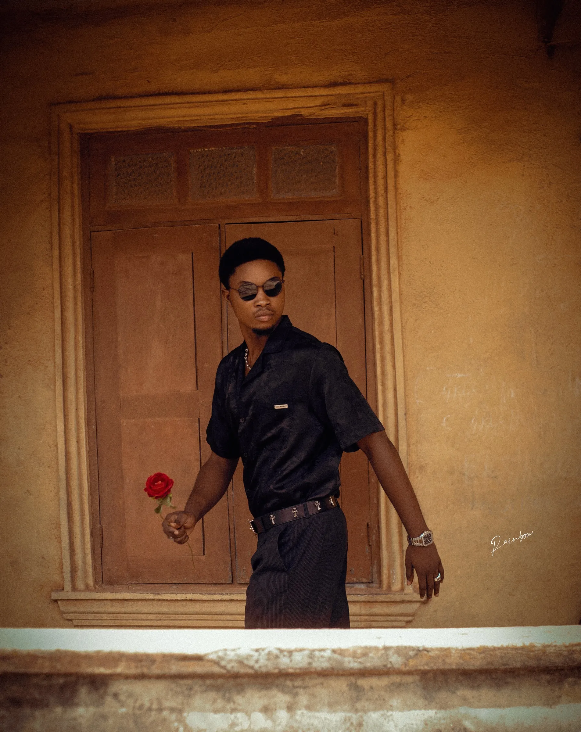 Man holding a rose at a balcony ledge