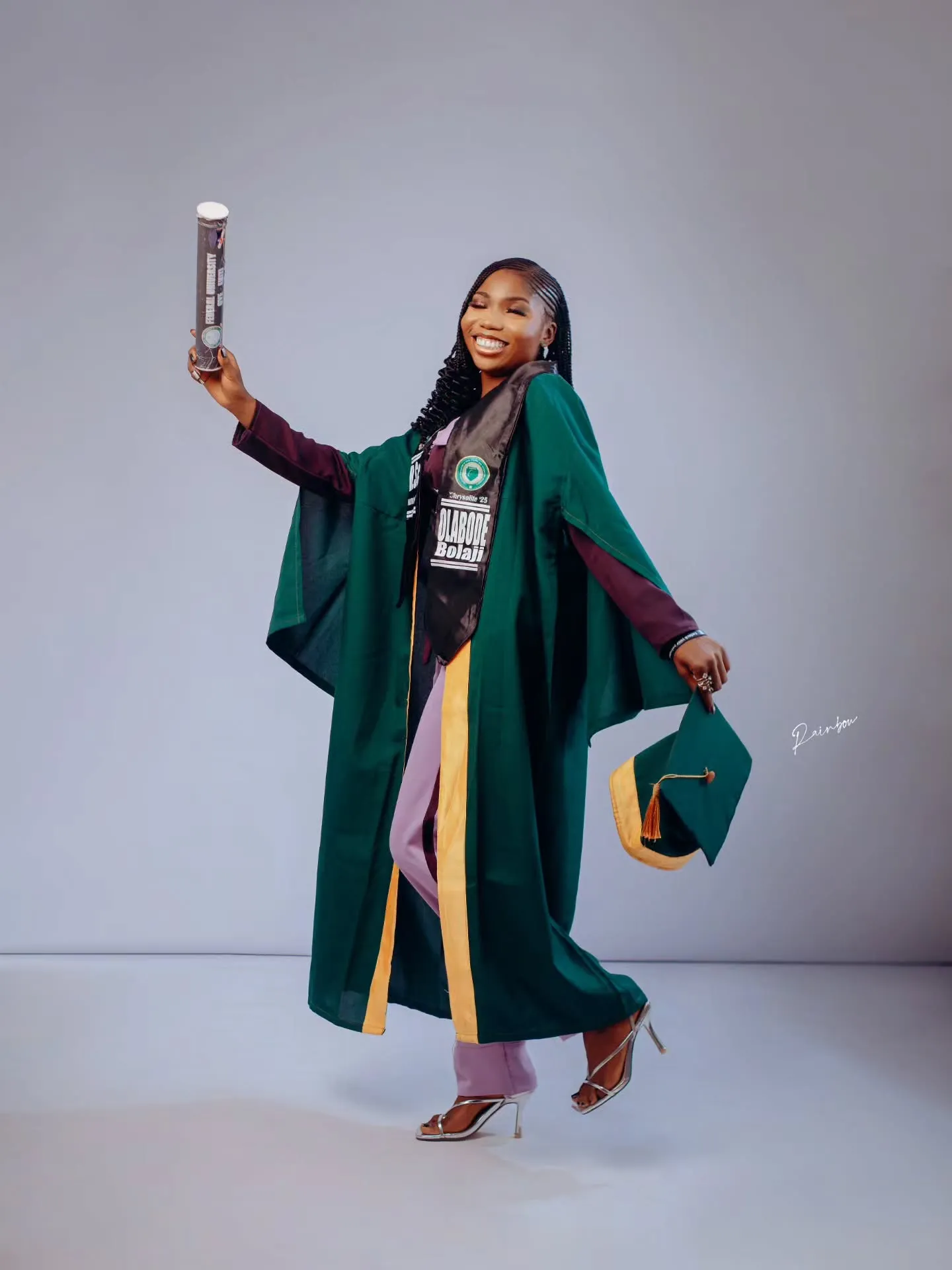 Graduate in green gown raising a scroll