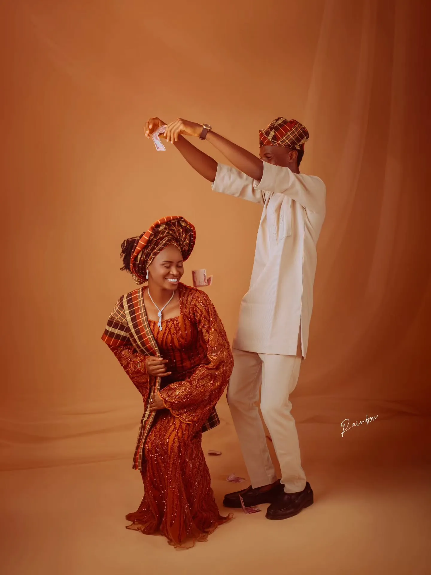 Groom twirling the bride in orange aso-oke