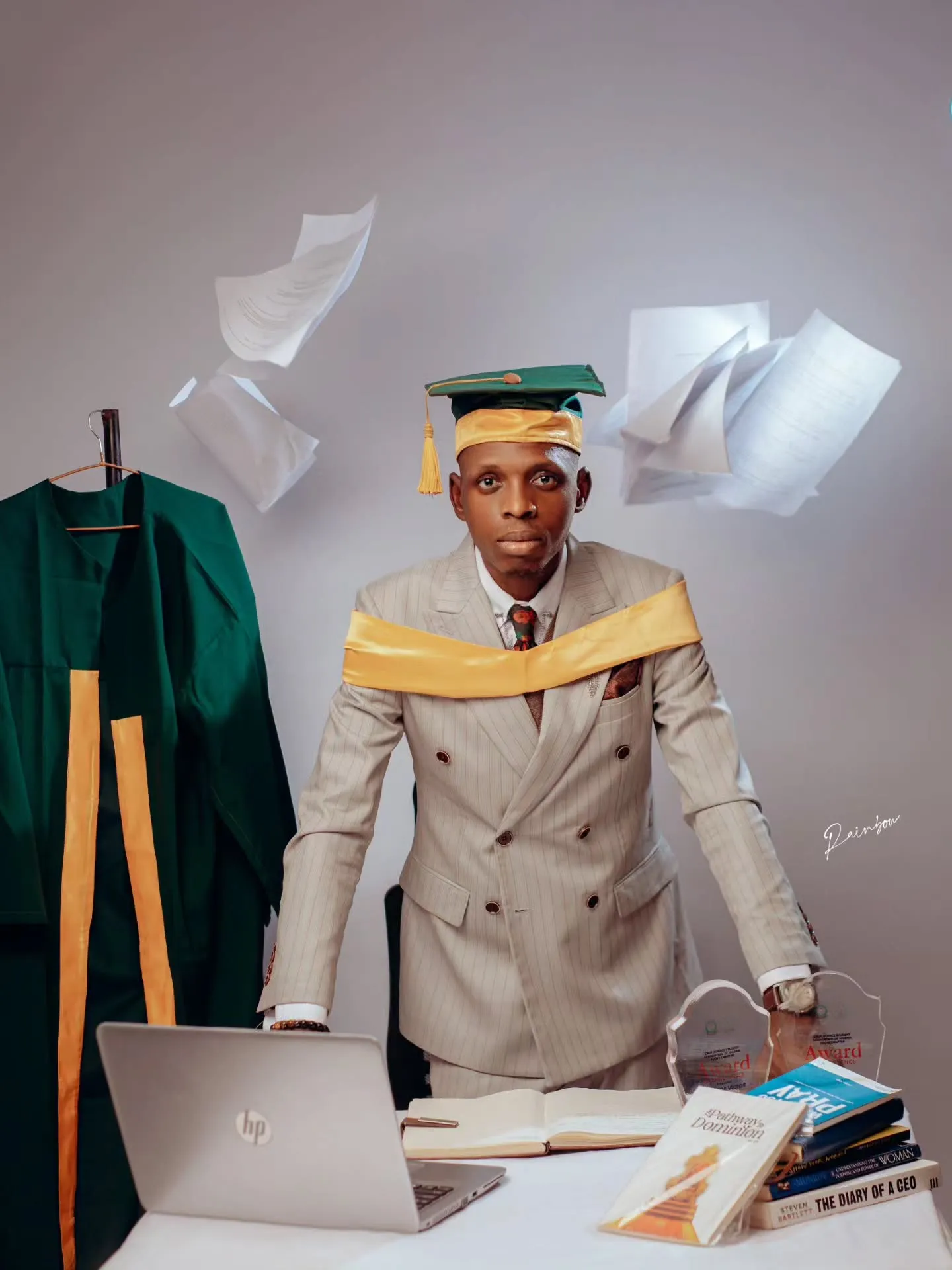 Graduate at a desk with papers flying