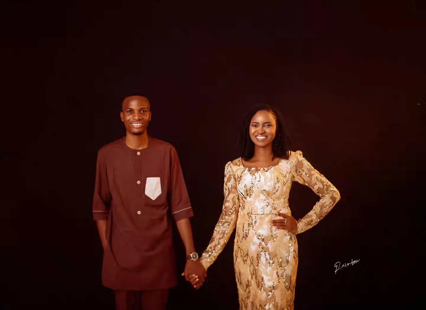 Couple holding hands against a dark backdrop